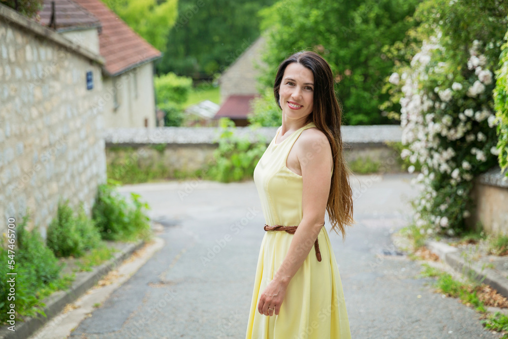 Lifestyle portrait of young stylish woman with long brunette hair walking on the street in old town, wearing yellow dress Lifestyle portrait of young stylish woman with long brunette hair walking on the street in old town, wearing yellow dress