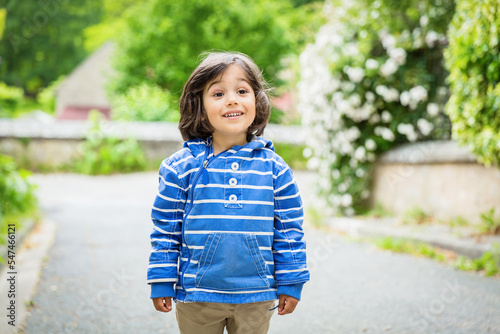 Little handsome baby boy staying outdoor in old town in France. Boy wearing blue jacket