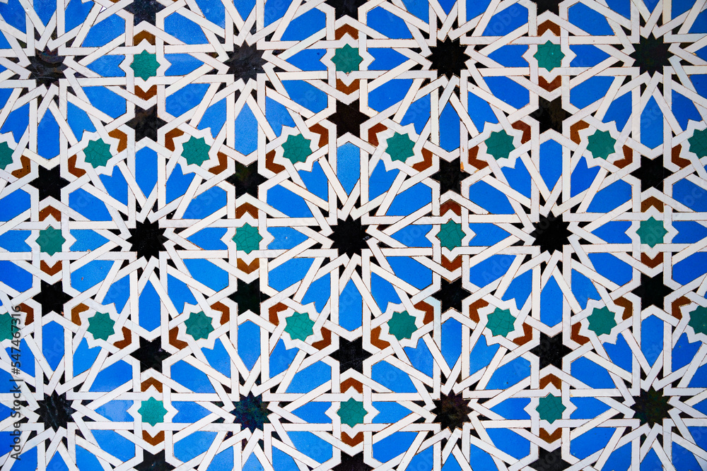 Geometric seamless andalusian moroccan islamic arabic star pattern in blue made out of ceramic tiles in Spain Sevilla