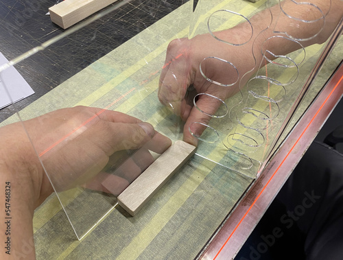Drive heated plexiglass with your hands. Production of a form for an advertising stand. Plastic bending on a nichrome heated spiral. Production of POS materials for advertising. photo