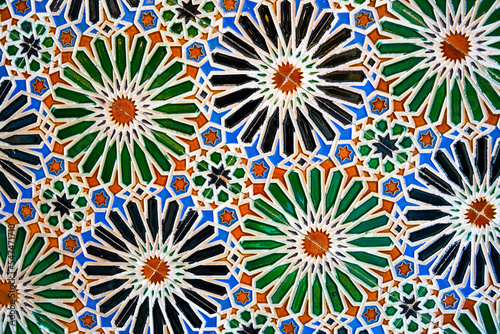 Geometric seamless andalusian moroccan islamic arabic round star floral pattern in green orange made out of ceramic tiles in Spain Sevilla photo