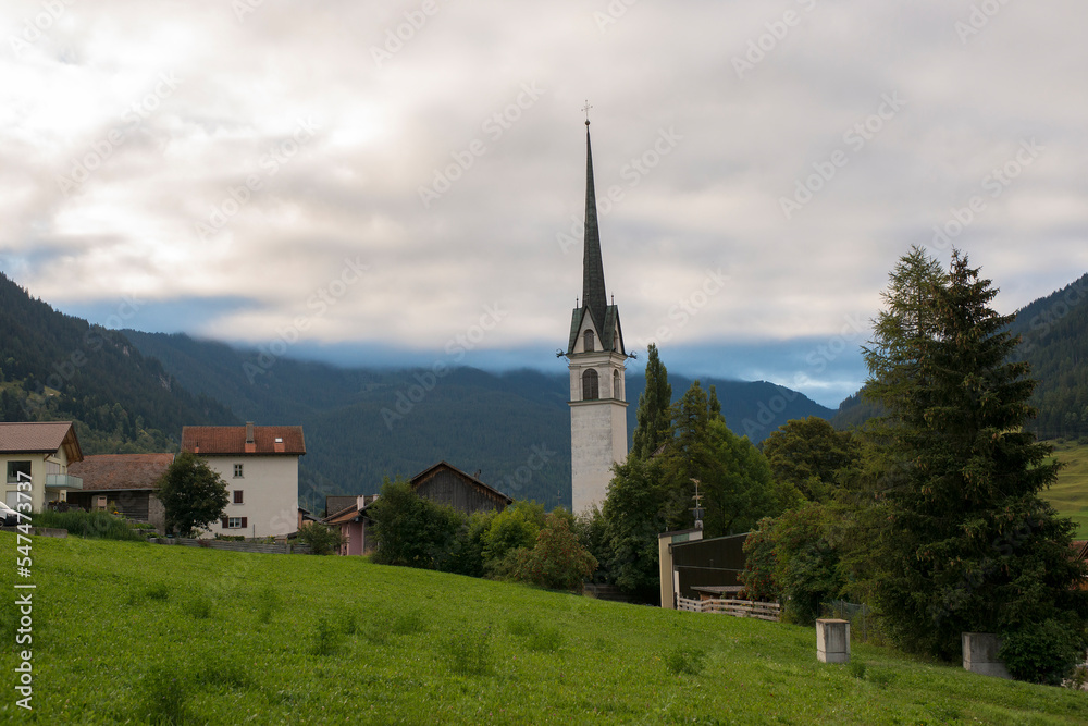 View on a church, tree and houses in Savognin, Graubünden, Switzerland
