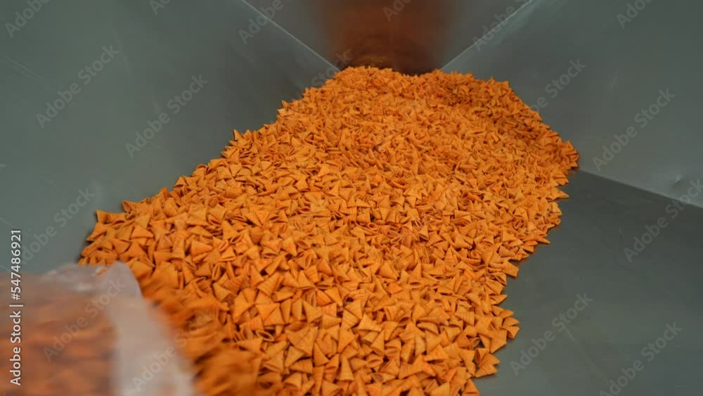 Pouring Cone shaped Chips Onto The Production Line In A Food Factory Pouring cone shaped chips onto the production line in a food factory