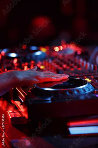 Party dj playing music in night club with professional cd turntables. Disc jockey mixing musical tracks on concert stage