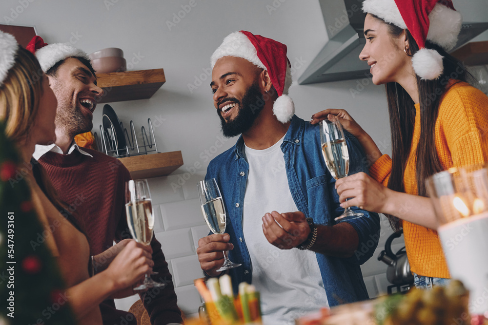 Happy young people communicating while enjoying Christmas dinner at home - obrazy, fototapety, plakaty 