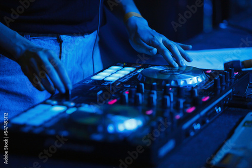 Female dj playing music set on night club party. Disc jockey woman plays hip hop on concert in nightclub.