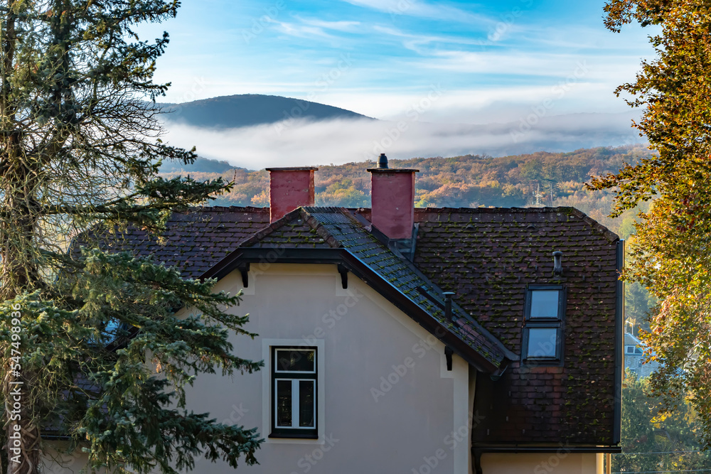 Part of an old country house on the background of mountains and fog at sunrise.