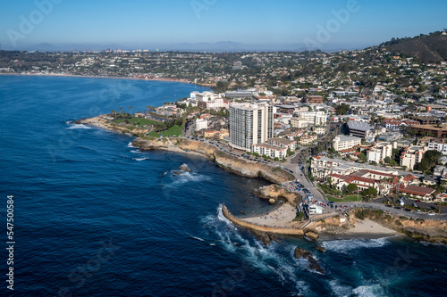 Aerial image of Children's Pool by Seal Rock in La Jolla San Diego California with mountains in the background and palm tree lined roads © Ashwin
