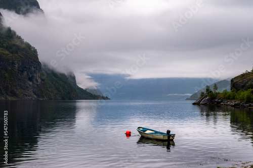 Personal boat anchored in fjord water in Aurlandfjord by Flam in Norway with rain clouds covering the mountains in the background