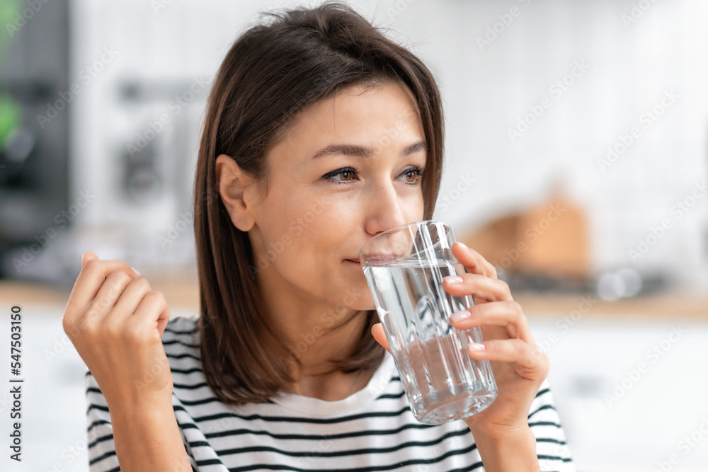 Portrait of a beautiful caucasian woman drinking fresh water, looks away. Healthy lifestyle concept Portrait of a beautiful caucasian woman drinking fresh water, looks away. Healthy lifestyle concept
