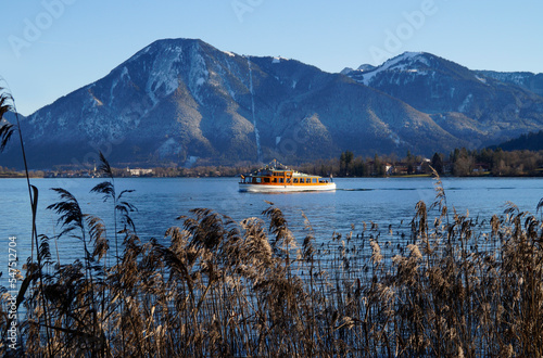 a sunlit little ship on alpine lake Tegernsee with its transparent turquoise waters in the Tegernsee valley in the Bavarian Alps against the blue sky (Bavaria, Germany)