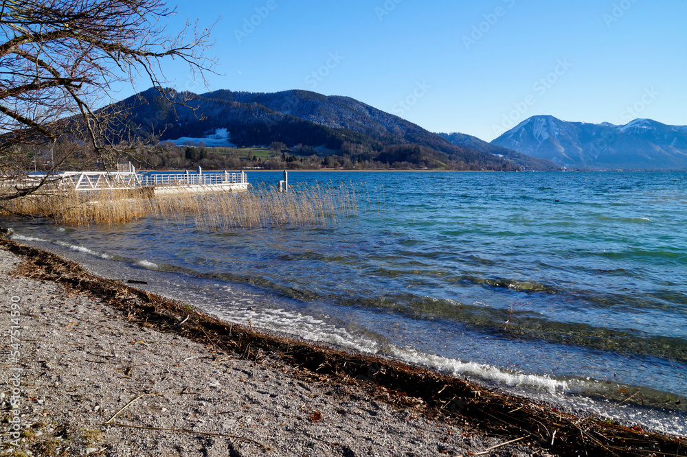 	
a sunny December day by alpine lake Tegernsee with its transparent turquoise waters in the Tegernsee valley in the Bavarian Alps against the blue sky (Bavaria, Germany)