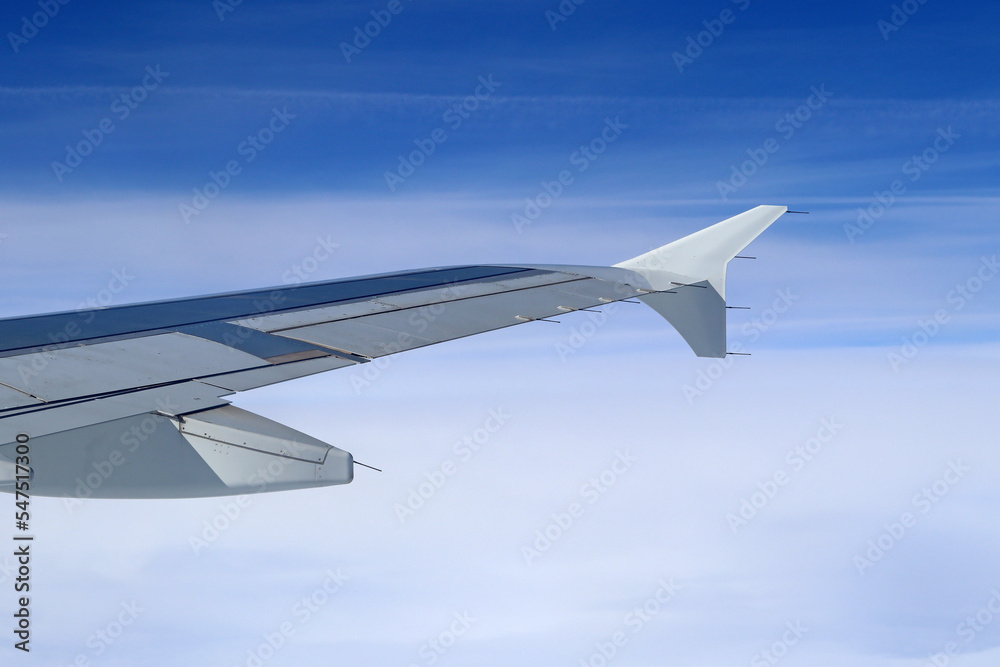 The wing end of a passenger plane under blue skies The wing end of a passenger plane under blue skies