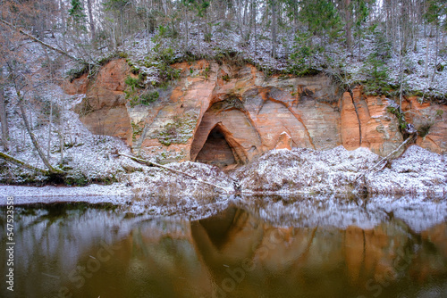 View to the Angels cave, a red sandstone cliff at the river Salaca in Skanaiskalns Nature Park in Mazsalaca in April in Latvia photo