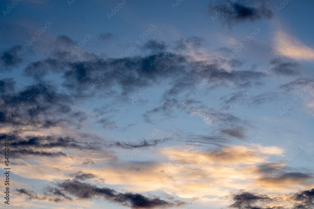 Bright blue cool autumn sky with light airy transparent clouds where some dark dramatic clouds create an eerie landscape