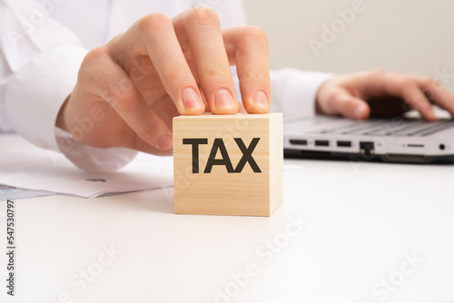 a wooden block with the letters TAX written on it on a white background
