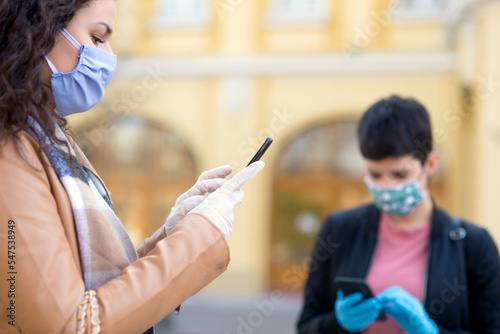 Two young women in the city wearing masks and gloves during corona virus pandemic