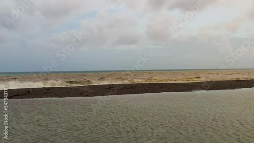 Brown Mountain River Flows Into the Blue Sea. Italy. View of the Mouth of the Razdelnaya River, Which Flows Into the Tyrrhenian Sea. A Unique Scenic Spectacle.  photo