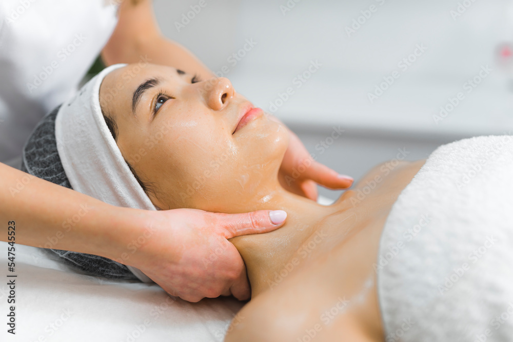 SPA and wellness day. Neck massage performed on attractive Asian woman in her 20s or 30s with beautiful shiny clear skin. Muscle tension and stress relief. Closeup shot. High quality photo
