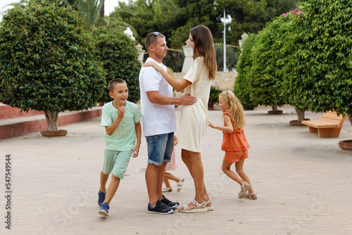 Family spending time together, cheerful parent with kids walking in the park in good weather