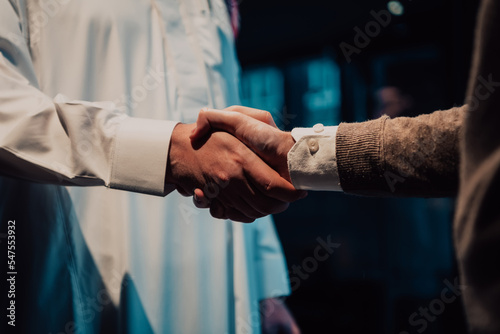 An elderly Arab man shaking hands with a businessman and ending a business meeting with successful business deals