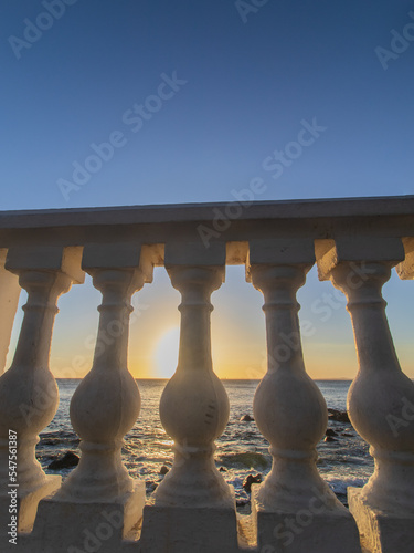 sunset over balustrade on the beach with a blue sky