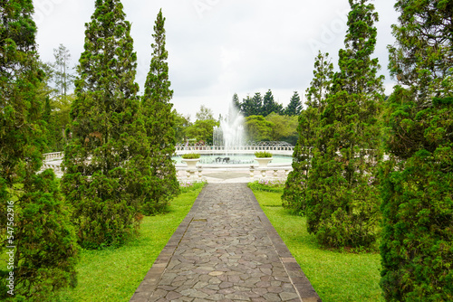 A walkway in a garden made of brick traverses the edge and amidst lawn or meadow in a flower garden. Tourist, travel, holiday and vacation spot Taman Bunga Nusantara, Cianjur, Indonesia