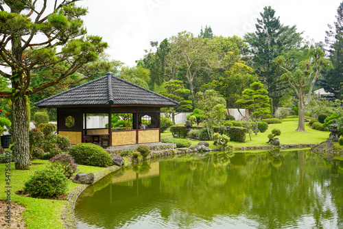 Traditional oriental park or garden from Japan or China with fish pond, lake or river, wooden bridge, meadow, and trees. Japanese garden design. Taman Bunga Nusantara, Cianjur, West Java, Indonesia.