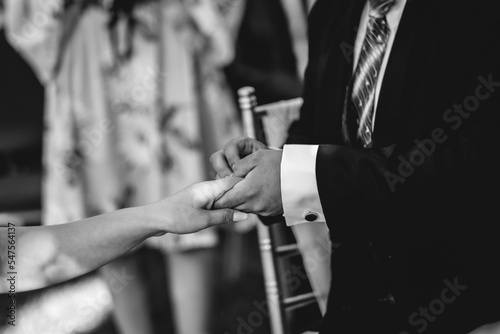 Details of hands of groom putting the wedding ring in the bride hand (in black and white)