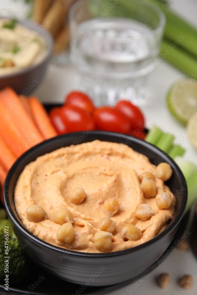 Plate with delicious hummus and fresh vegetables on white table, closeup Plate with delicious hummus and fresh vegetables on white table, closeup