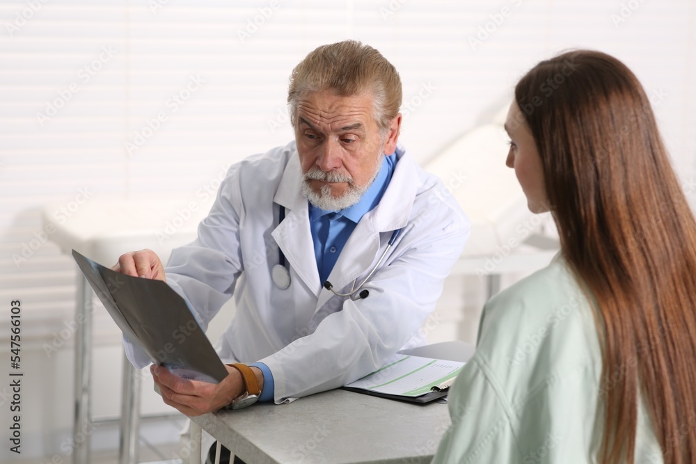 Orthopedist showing X-ray picture to patient in clinic Orthopedist showing X-ray picture to patient in clinic