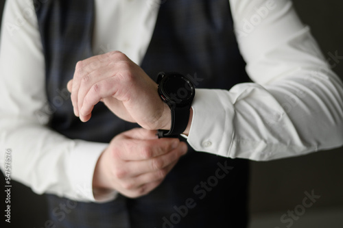 A man straightens a watch strap, close-up. Young modern businessman. Business style clothing concept, wedding