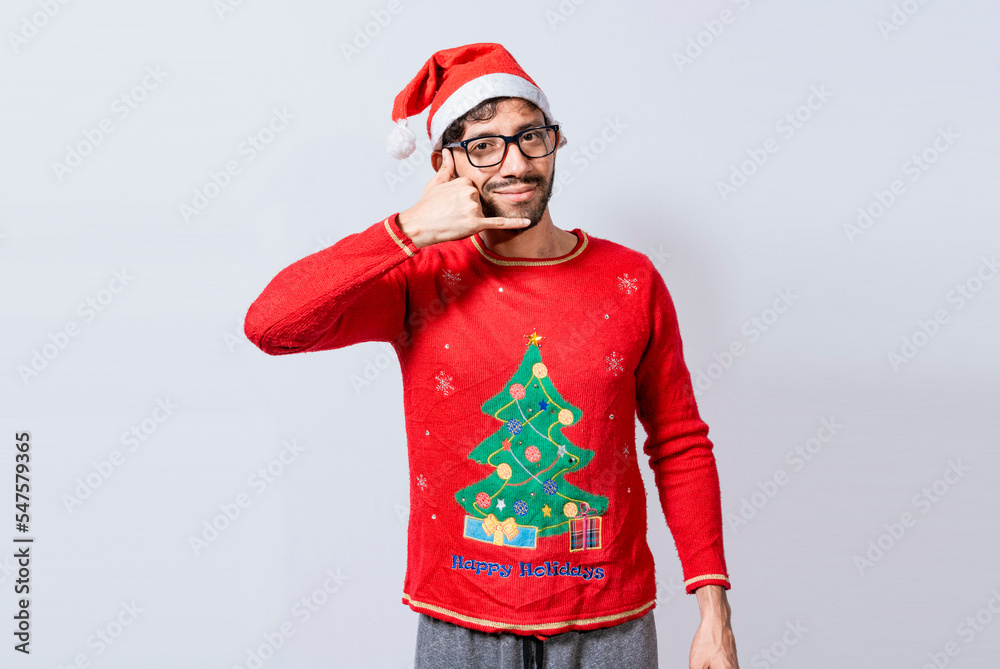 Obraz premium People in Christmas clothes making a call gesture with their fingers. Man in christmas hat imitating a phone conversation, Young latin man in christmas hat making a call gesture isolated