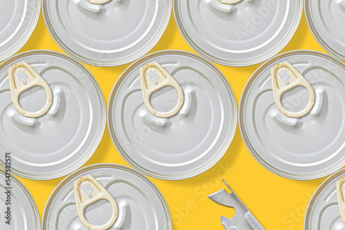 Canned food and can opener on yellow background.