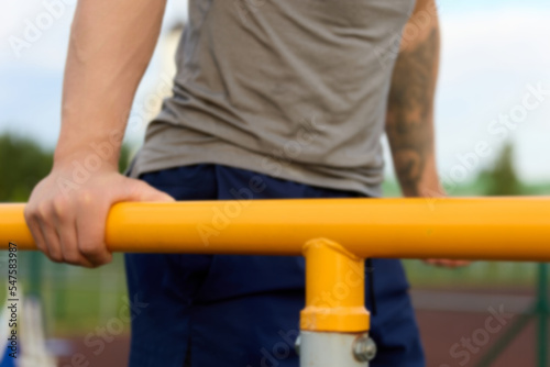 Close-up of a man in sportswear performing gymnastic exercises on push-ups on parallel bars. Summer training of an athlete on the yellow bars before the competition