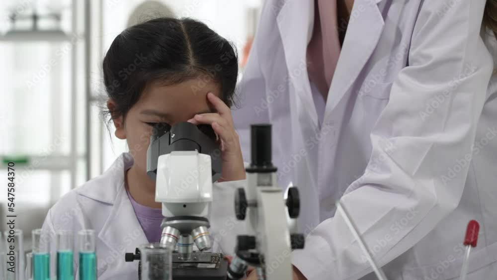 Asian Child learning to Use Microscope with Teacher in Science Classroom Asian Child learning to Use Microscope with Teacher in Science Classroom