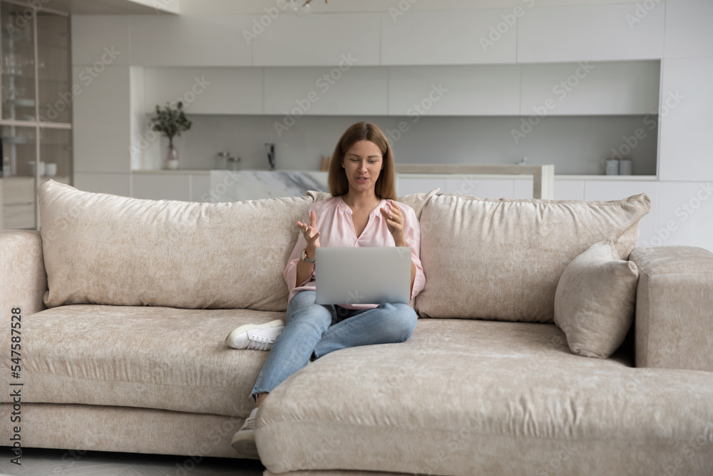Attractive woman makes video call, talks to friend or by business sit on sofa with laptop. Virtual meeting with family, easy comfort method for communication using modern tech and internet connection Attractive woman makes video call, talks to friend or by business sit on sofa with laptop. Virtual meeting with family, easy comfort method for communication using modern tech and internet connection