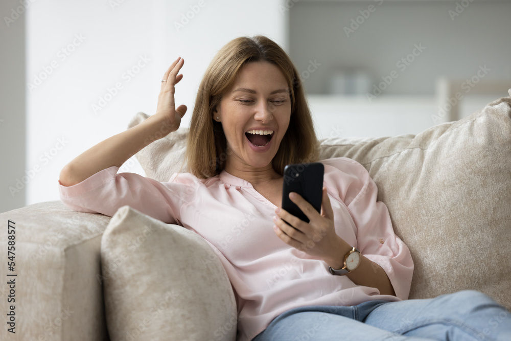 Young woman holds smartphone looks overjoyed celebrate great news in sms. Bet victory, got huge discount, personal achievement and success, receive long-awaited answer, enjoy moment of win feels happy