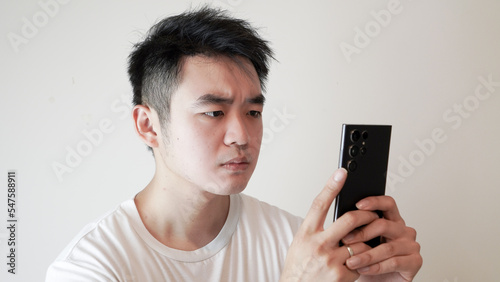 an asian or caucasian man wearing plain white t shirt was typing on his phone isolated over a white background photo