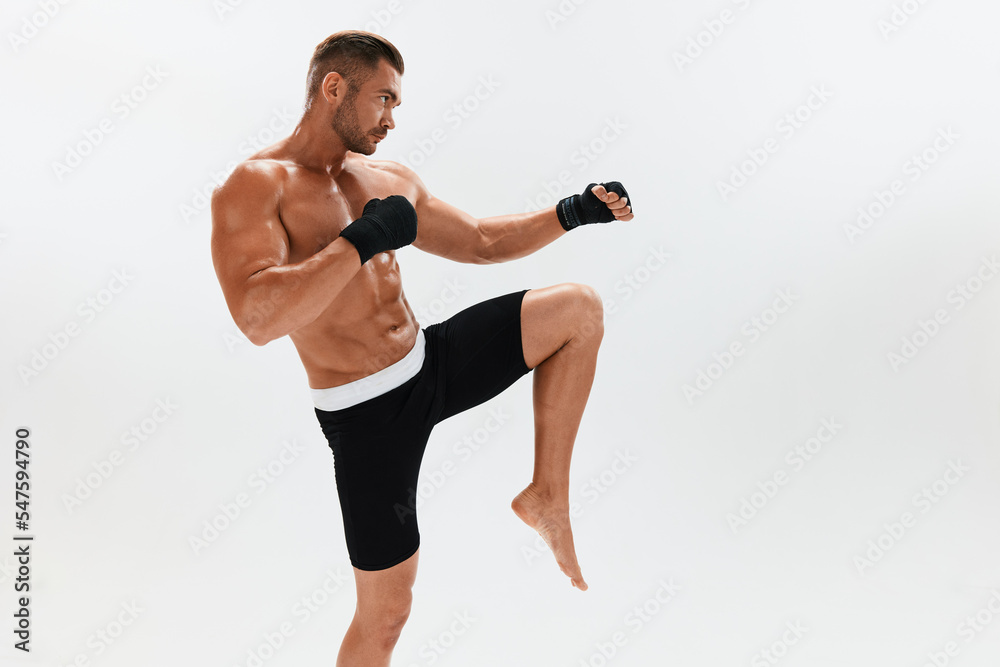 Man athletic bodybuilder poses in boxing gloves with nude torso abs in full-length background, boxing and martial arts. Advertising, sports, active lifestyle, light, competition, challenge concept. Man athletic bodybuilder poses in boxing gloves with nude torso abs in full-length background, boxing and martial arts. Advertising, sports, active lifestyle, light, competition, challenge concept.