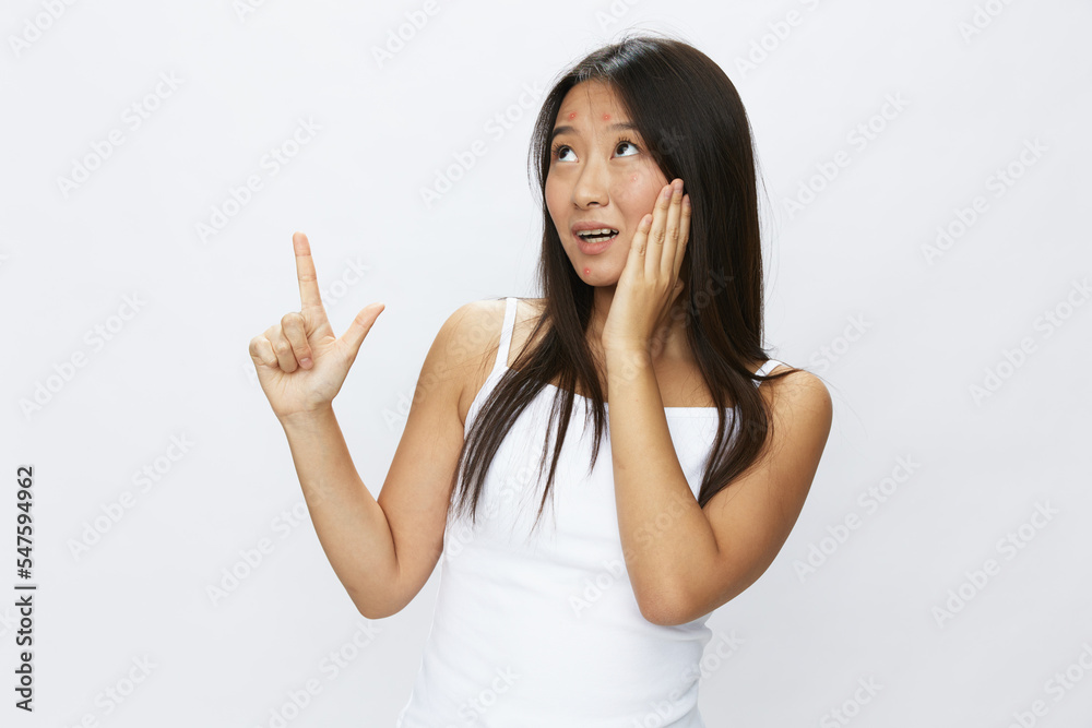 Asian woman hand signals, finger pointing facial skin problems, acne and inflammation, red rash and allergies, chicken pox, sadness from rashes. Facial skin care concept for diseases and nerves Asian woman hand signals, finger pointing facial skin problems, acne and inflammation, red rash and allergies, chicken pox, sadness from rashes. Facial skin care concept for diseases and nerves