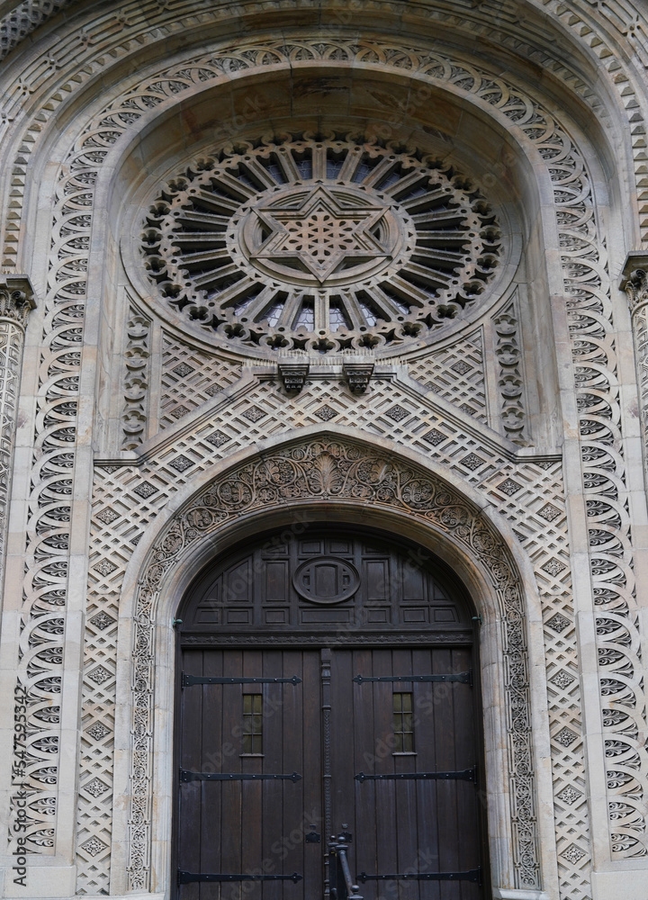 Front door of old synagogue surrounded by intricate geometric decorations in stone
