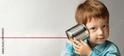 happy boy play in the tin can phone, boy attached a telephone to his ear photo