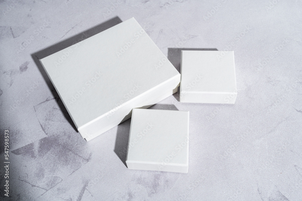 Three white square gift boxes mockup on gray concrete background. From above, closeup, top view, minimalist concept Three white square gift boxes mockup on gray concrete background. From above, closeup, top view, minimalist concept