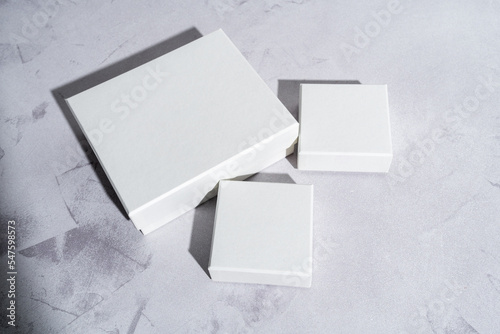 Three white square gift boxes mockup on gray concrete background. From above, closeup,  top view, minimalist concept