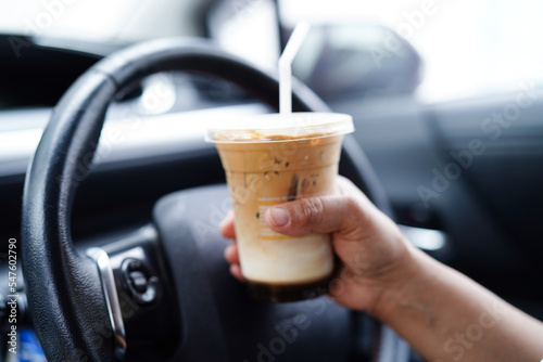 Bangkok, Thailand - May 15, 2022 Asian woman driver hold ice coffee cup for drink in car, dangerous and risk an accident.