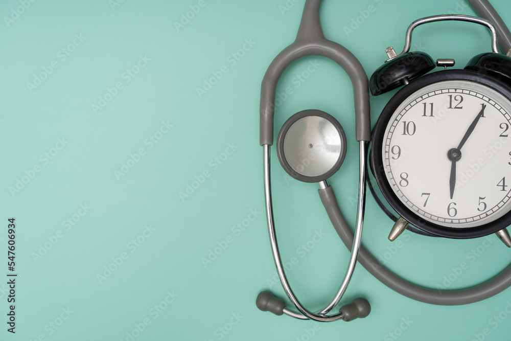 Top view of stethoscope and alarm clock on the green background, schedule to check up healthy concept