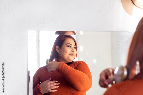 fat hispanic young woman in front of mirror combing her hair. plus size latina model photo