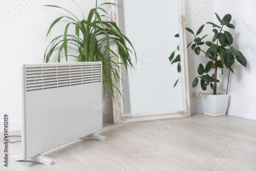 plant and electric heating battery on a gray background, harm dry air for houseplants concept, heating season