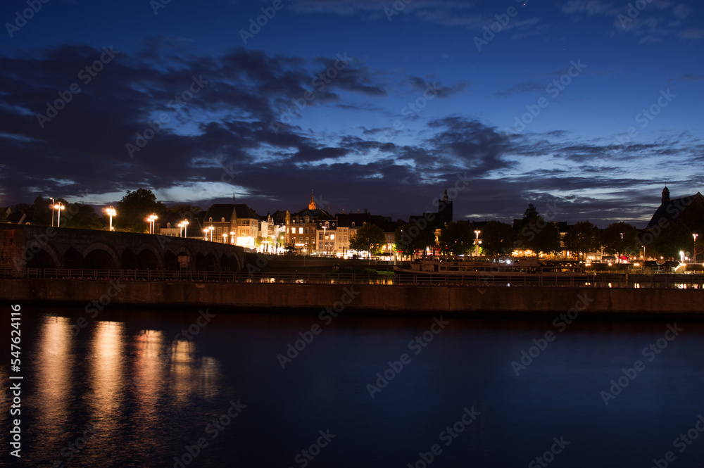 Cityscape of the center of Maastricht in twilight in the Netherlands with in the foreground the river Meuse